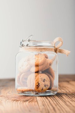 Büyük kavanoz ahşap bir masa üzerinde duran yulaf kurabiye dolu. Düz arka plan. Dikey yazdırma yönü