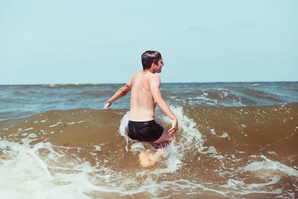 Yüksek dalgalar deniz yaz tatil sırasında zevk genç adam. Deniz kenarında bir yaz tatili harcama