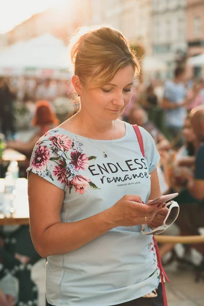 Улыбающаяся Женщина Мобильного Телефона Стоящая Переполненном Центре Города Освещенная Солнцем — стоковое фото