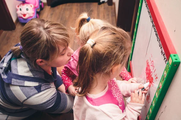 Children drawing a pictures learning a letters playing together using whiteboard and markers