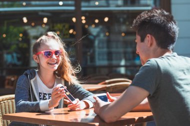 Genç kadın ve adam Kaldırım Café konuşuyor ve kullanarak m oturan