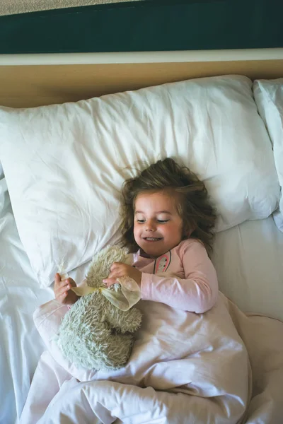 Holčička, která ležela ráno v posteli s medvídkem — Stock fotografie