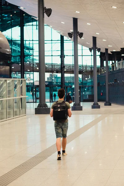 Young man walking in the railway station, travelling with backpa