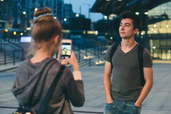 Mujer joven tomando fotos de su amigo, usando un teléfono inteligente — Foto de Stock