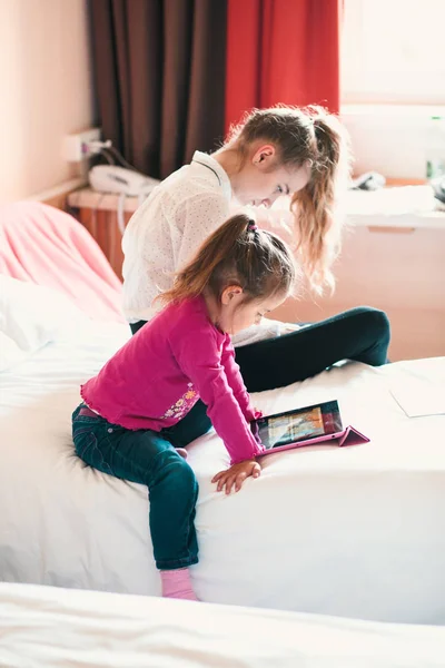 Tiener meisje met behulp van mobiele telefoon samen met haar zusje — Stockfoto