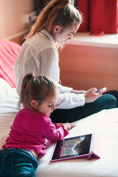 Tiener meisje met behulp van mobiele telefoon samen met haar zusje — Stockfoto
