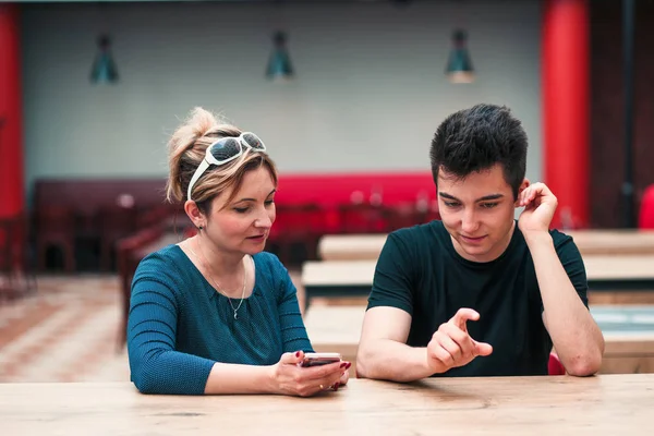 Woman and young man talking together and using mobile phones — Stok fotoğraf