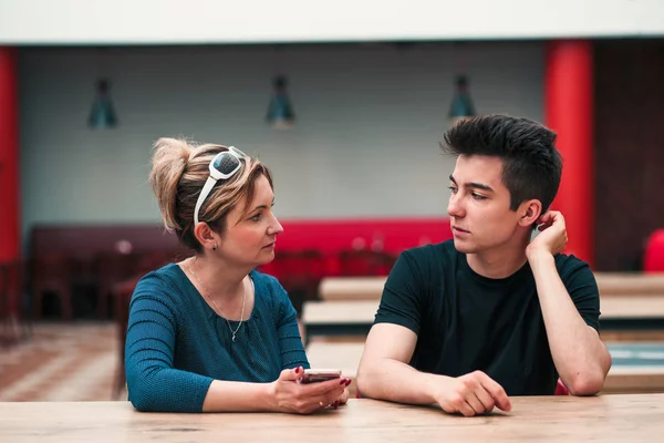 Femme et jeune homme parlent ensemble et utilisent des téléphones mobiles — Photo