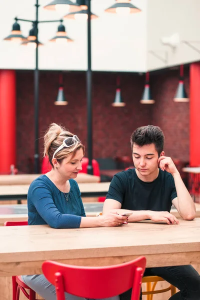 Woman and young man talking together and using mobile phones — Stok fotoğraf