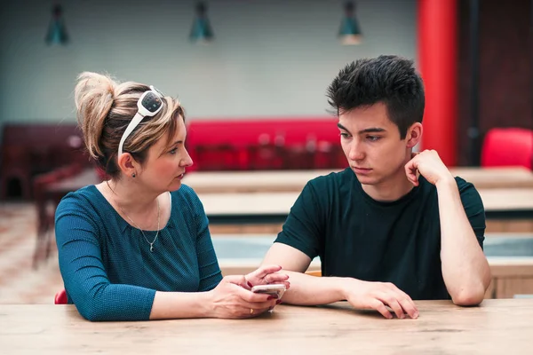 Femme et jeune homme parlent ensemble et utilisent des téléphones mobiles — Photo