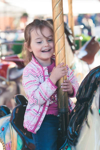 Petite adorable fille souriante chevauchant un cheval sur rond-point carous — Photo