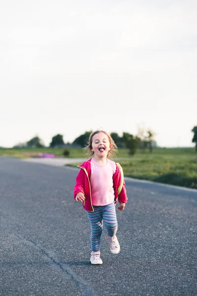 Pequena menina adorável se divertindo correndo na estrada, colando-a para — Fotografia de Stock
