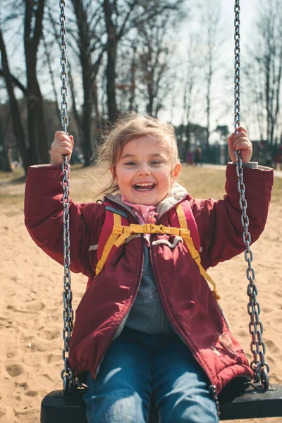Pouco sorrindo menina feliz balançando em um parque na primavera ensolarada da — Fotografia de Stock