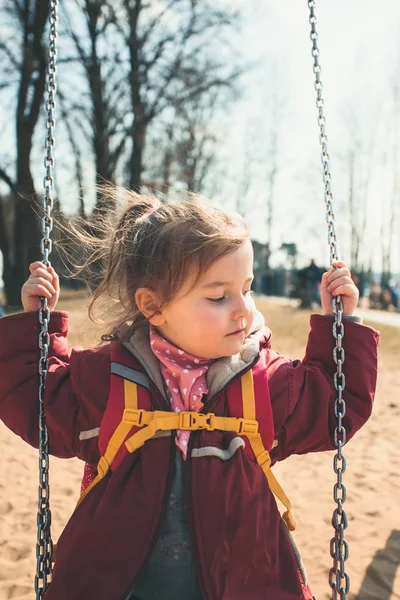 Pequeña linda chica balanceándose en un parque en soleado día de primavera —  Fotos de Stock