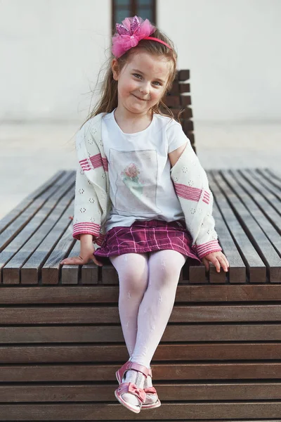 Porträtt av söt bedårande liten flicka sitter på bänken i CE — Stockfoto