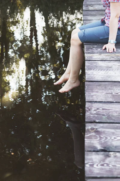 Femme assise sur un pont au-dessus d'un lac pendant les vacances d'été — Photo