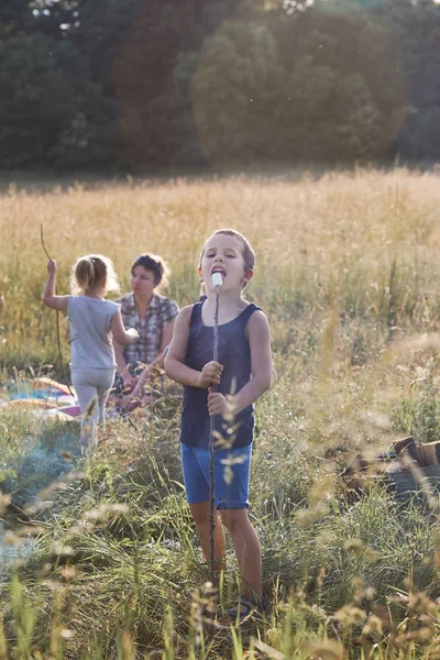 Pojke äter en marshmallow efter stekning det över en lägereld — Stockfoto