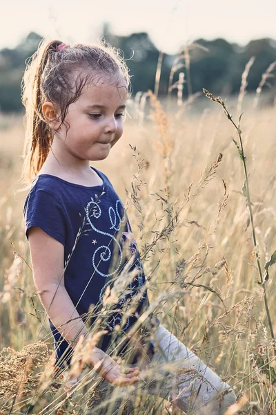 Malá šťastná usměvavá holka, co hraje vysokou trávu — Stock fotografie