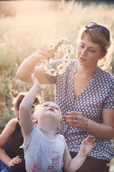 Matka položila na hlavu malého GIR korunku divokých květin — Stock fotografie