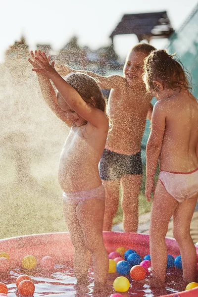Niños pequeños disfrutando de un agua fría rociada por su padre — Foto de Stock