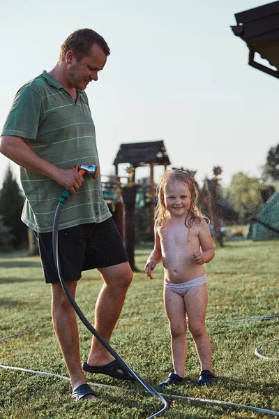 Menina desfrutando de uma água fria pulverizada por seu pai — Fotografia de Stock