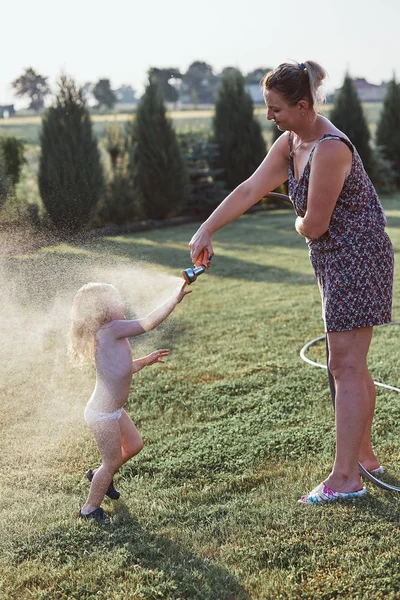 Holčička si vychutnávala chladnou vodu, postříkala ji matka — Stock fotografie