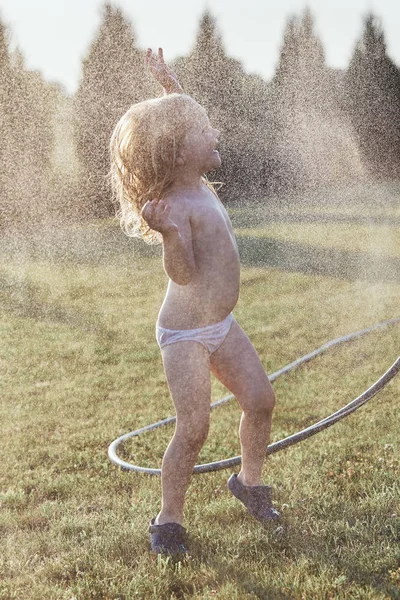 Little girl enjoying a cool water sprayed by her mother — Stock Photo, Image