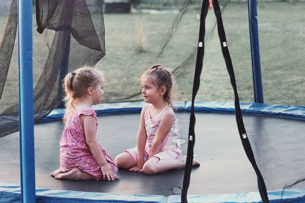 Dos niñas lindas jugando en el trampolín en el patio trasero —  Fotos de Stock
