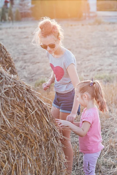 Systrar leker med hö Bale tillsammans utomhus i Yo — Stockfoto