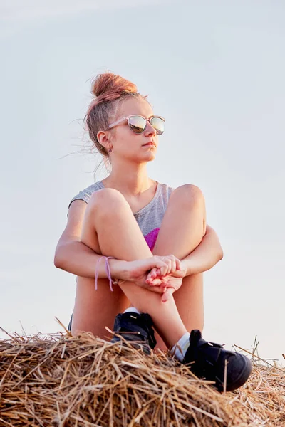 Adolescente sentada en una bala de heno al atardecer — Foto de Stock