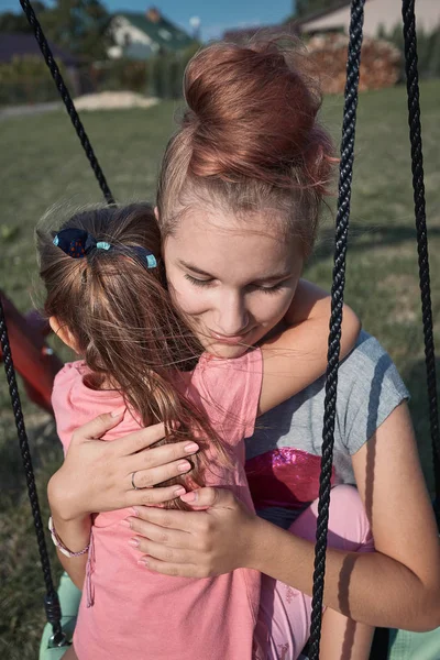 Adolescente menina abraçando sua irmã mais nova — Fotografia de Stock