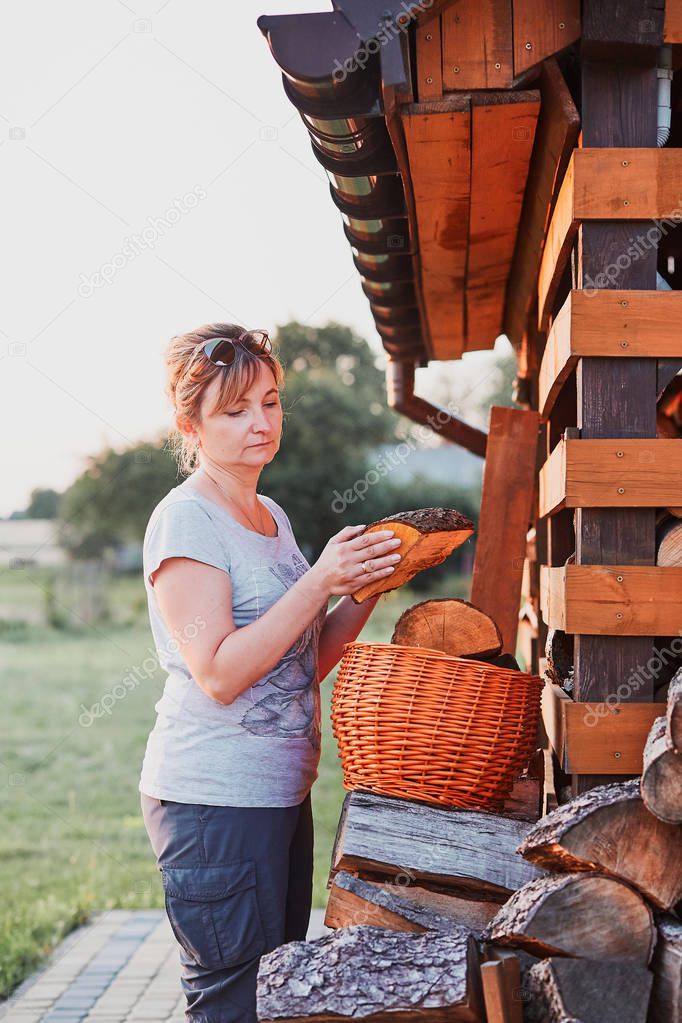 Woman putting the wood logs to wicker basket