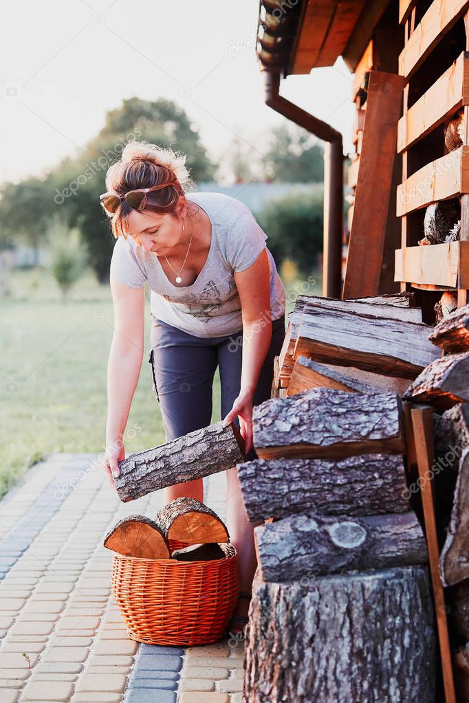 Woman putting the wood logs to wicker basket