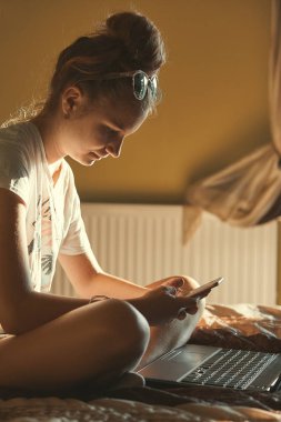 Taşınabilir bilgisayar ve cep telefonu kullanan genç kadın