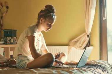 Taşınabilir bilgisayar ve cep telefonu kullanan genç kadın