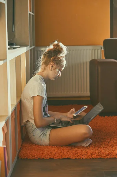 Mujer joven usando ordenador portátil y teléfono móvil — Foto de Stock
