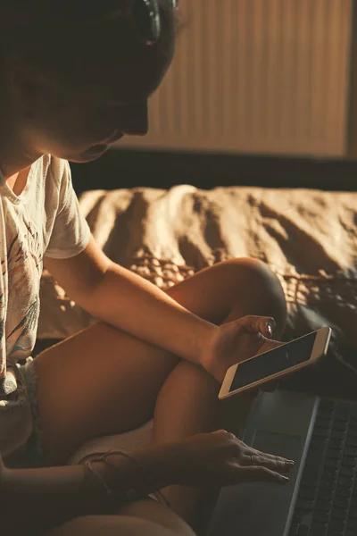 Junge Frau benutzt tragbaren Computer und Handy — Stockfoto