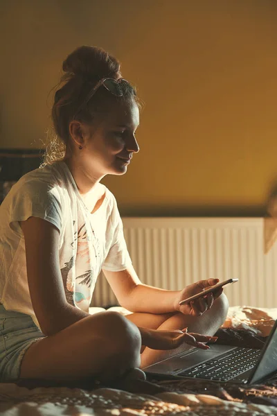 Mujer joven usando ordenador portátil y teléfono móvil — Foto de Stock