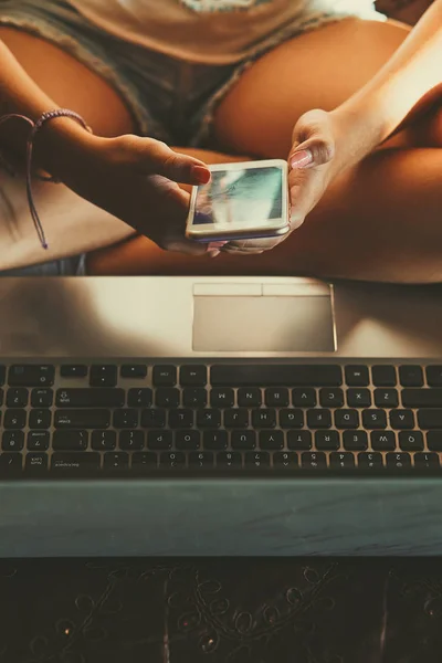 Mladá žena používající přenosný počítač a mobilní telefon — Stock fotografie