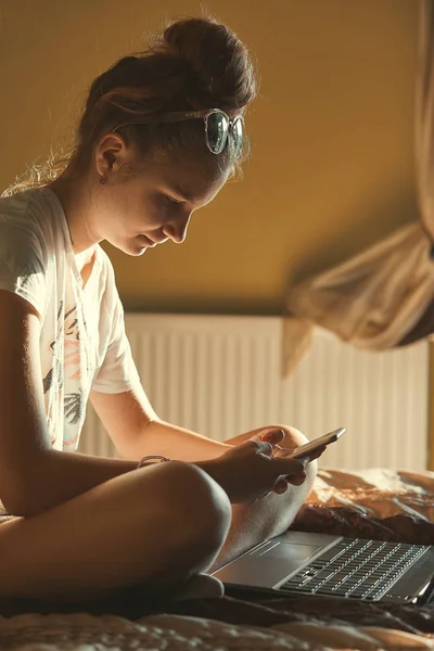 Mujer joven usando ordenador portátil y teléfono móvil —  Fotos de Stock