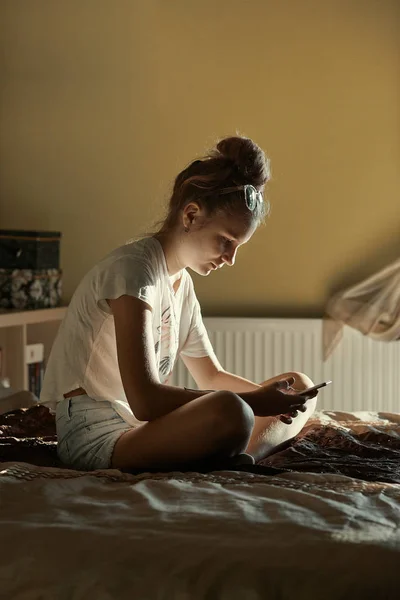 Jovem mulher usando computador portátil e telefone celular — Fotografia de Stock