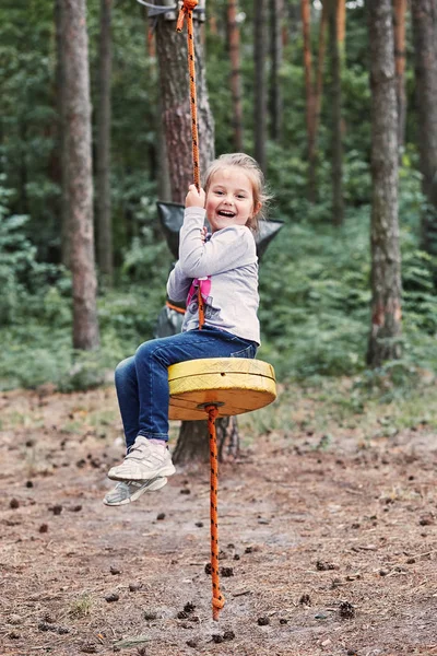 Chica feliz montando en la tirolina en el parque de cuerdas —  Fotos de Stock