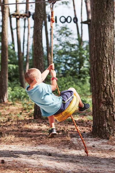 Felice ragazzo cavalcando sulla zip line nel parco corda — Foto Stock