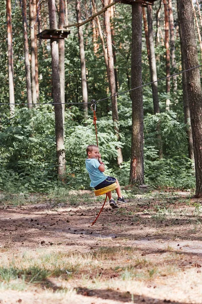 Joyeux garçon chevauchant sur la tyrolienne dans le parc de corde — Photo