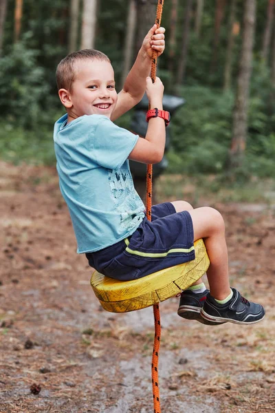 Felice ragazzo cavalcando sulla zip line nel parco corda — Foto Stock