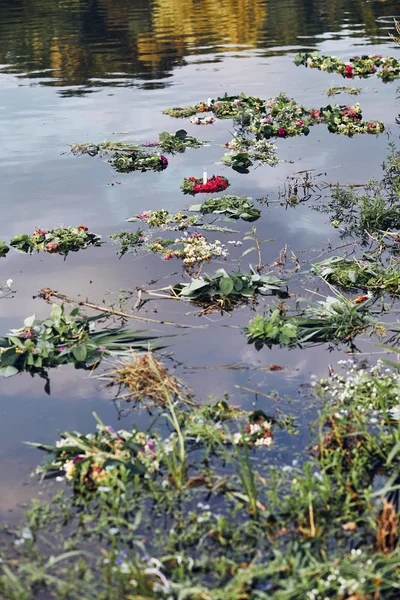 Wreaths of flowers and herbs floating on river