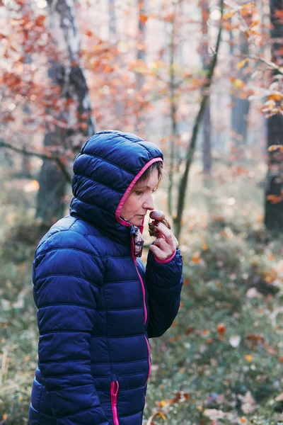 Femme sentant un champignon cueilli dans la forêt — Photo