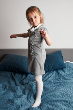 Kulaklıkla şarkı söyleyen küçük kız kendini gerçek bir şarkıcı gibi gösteriyor. Çocuk zıplayarak, dans ederek, yatakta müzik dinleyerek eğleniyor.