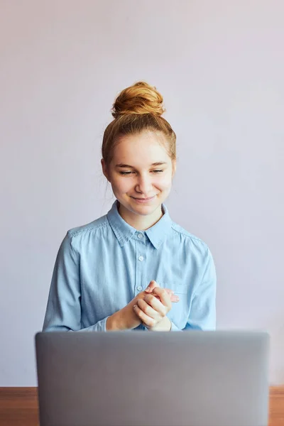 Young woman student having classes, learning online, watching lesson remotely, listening to professor, talking with classmates on video call from home during quarantine. Young girl using laptop sitting at a desk