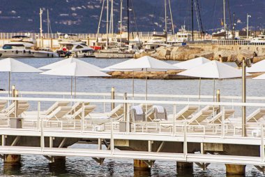 Cannes 'da yat tekneleri ve plaj şemsiyesi bulunan deniz Körfezi ve iskele